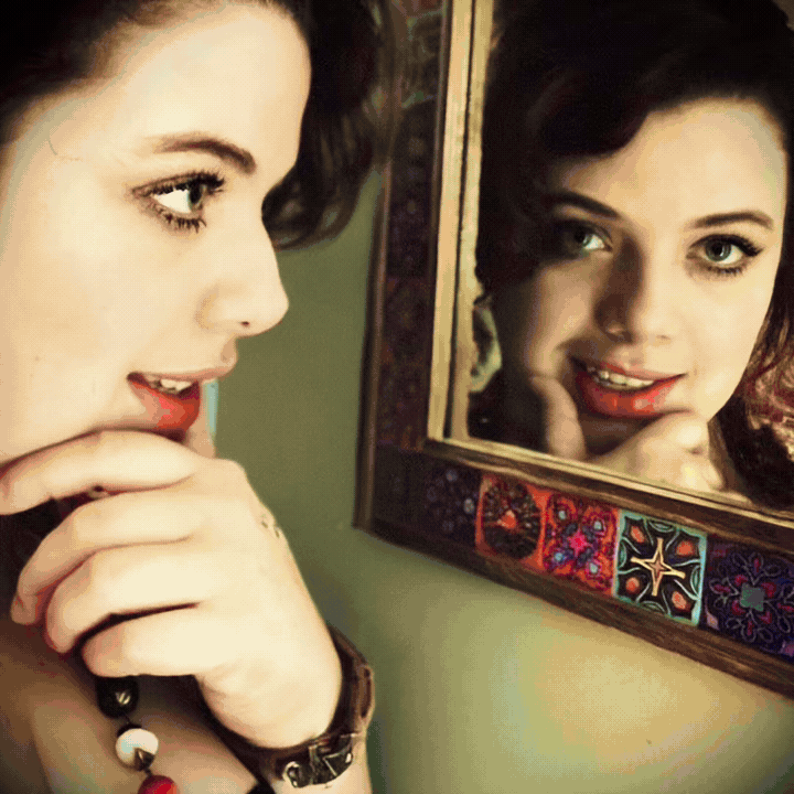 A short loop of Ania Mira and her reflection. The picture moves from warm light, to a violet reverse, through a bright flare, into blue, then starts again.